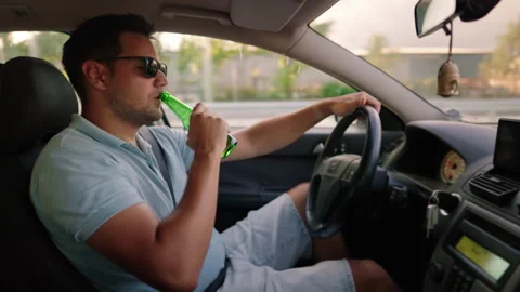 Drink and drive. man drinks alcohol while driving a car. Illegal drunk driving. Video stock 280320349