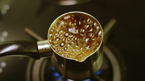 Drink boils in cezve coffeemaker standing on black burner Stock Footage 230037888
