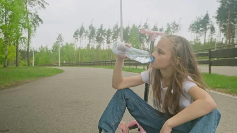 Drink during training, physical activity. Little girl drinks water after riding  Stock Footage 277548663