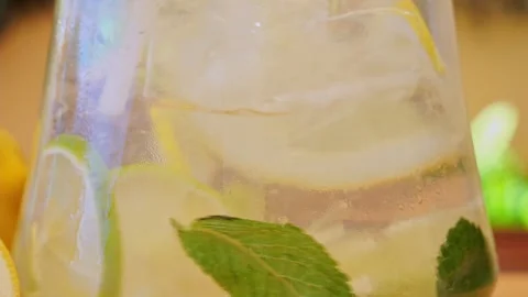 Drink with Ice, Mint, lemon, lime in a glass decanter. Outdoors. close up Stock Footage 274665942