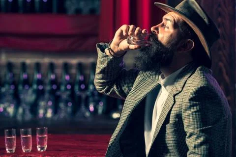 A drink for the man. Close up of a man drinking whiskey at the bar. Alcoholic Stock Photos