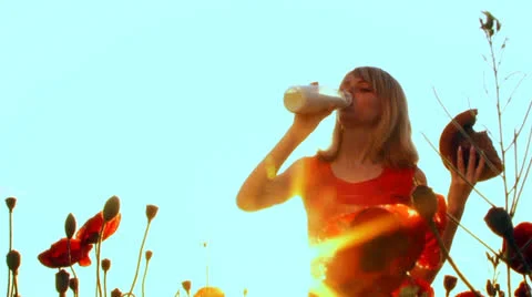 Drink milk and eats bread in a poppy field. Stock-Footage 22457584