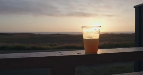 Drink in plastic cup on a patio with a sunset view 스톡 동영상 310410451
