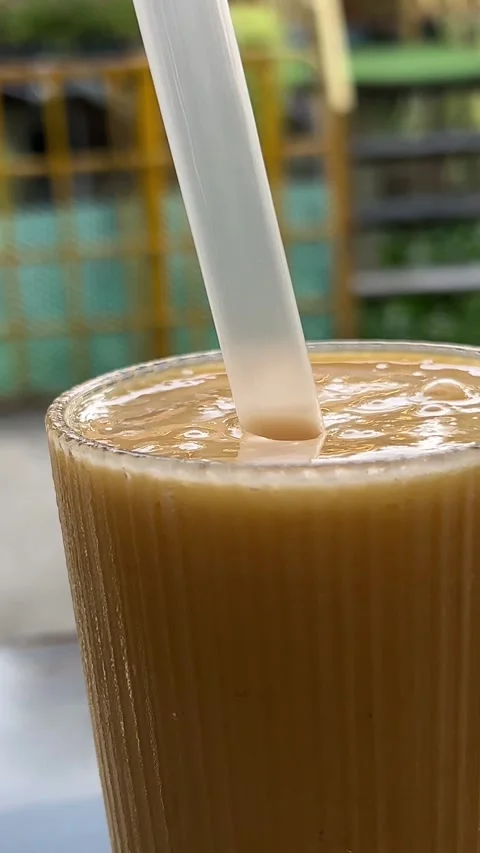 Drink from a plastic glass through a straw girl drinks a milkshake from a Stock Footage 316087847