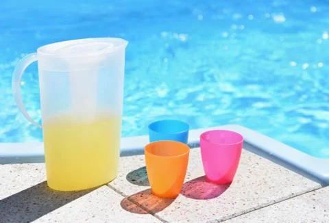 Drink in a teapot with cups at the pool. Drinking water in the hot summer. Stock Photos
