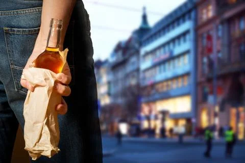 Drinker hiding bottle of spirits in the paper bag Stock Photos