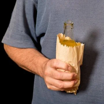 Drinker holds a bottle in the paper bag Stock Photos
