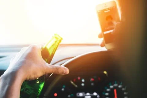 Drinking and driving ,man drinking alcohol and using mobile phone while driving Stock Photos