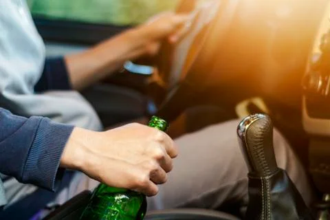 Drinking and driving ,man drinking alcohol and using mobile phone while driving Stock Photos