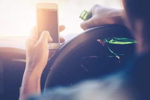 Drinking and driving ,man drinking alcohol and using mobile phone while driving Stock Photos