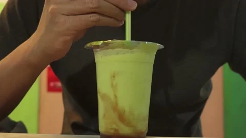 Drinking Avocado Juice Using Straw on a Plastic Cup Stock Footage 197480924