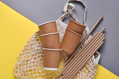 Drinking brown tubes straws made of paper and cornstarch, mesh market bag and Stock Photos