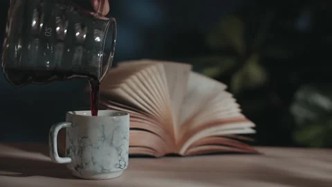 Drinking Coffee and Reading Book Concept. Pouring Hot Coffee from the Jar int 库存影片 130953015