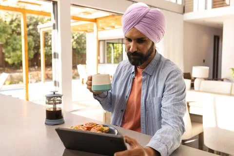 Drinking coffee and using tablet, man enjoying breakfast at home Stock Photos
