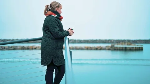 Drinking coffee from a cup in cold weather while standing next to the sea Stock Footage 122246540