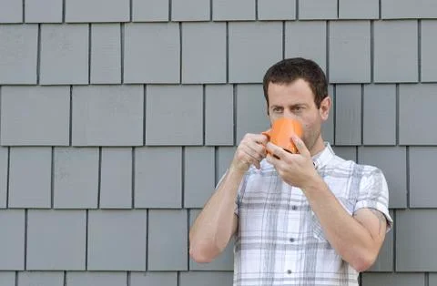 Drinking coffee outside in front of a gray background. Stock Photos