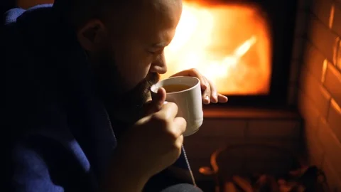Drinking cup of hot tea at home near fireplace. Cozy hygge scene Stock Footage 125092992