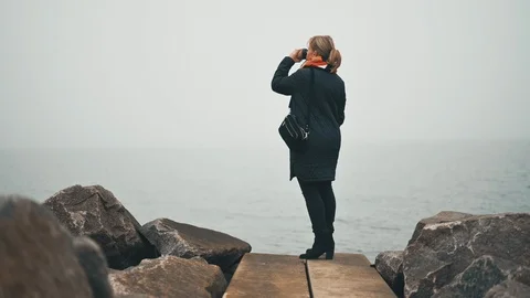 Drinking hot drink outside in cold weather next to sea Stock Footage 122259391