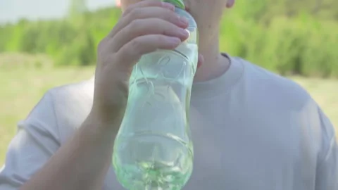 Drinking liquid from a bottle on a summer day Stock Footage 240278060