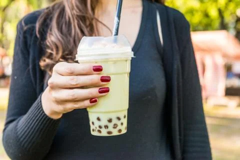 Drinking matcha bubble chai latte tea at a street food market. Stock Photos