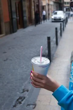 Drinking plastic cup with a straw and a hand, vertical 写真素材
