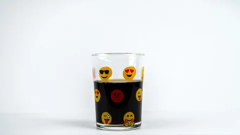 Drinking of soda from emoji patterned glass cup on white background Stock Footage 129324573