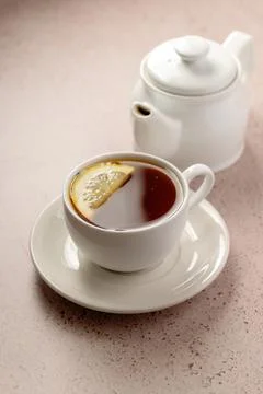 Drinking tea, white ceramic cup and tea pot with black tea and lemon slice. Stock-Fotos