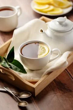 Drinking tea, white ceramic cup and tea pot with black tea and lemon slice. Foto stock