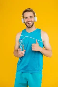 Drinking water. Cheerful athletic guy listening music. Keep body and mind in Foto stock