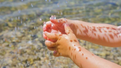 Drinking water drops falling on childs hands. Little hands playing with drops of Stock Footage 120788613
