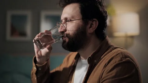 Drinking water. Handsome bearded man drinks water. Happy millennial quenches his Stockbeeldmateriaal 196202587