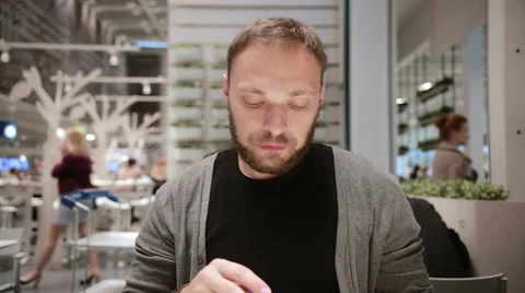 Drinking water. Handsome man with a beard opening a bottle of water sitting in a Stock Footage 67954321