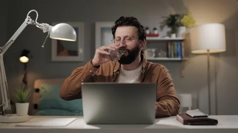 Drinking water. Happy man drinks water. Bearded remote worker in home office Stock-Footage 196201834