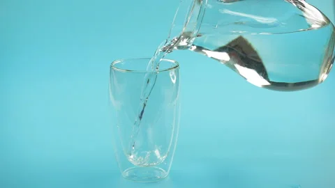 Drinking water is poured into a glass in slow motion Stock Footage