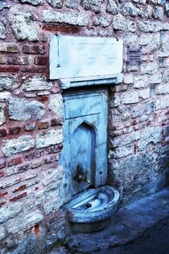 Drinking water tap in a brick wall. Stock Photos