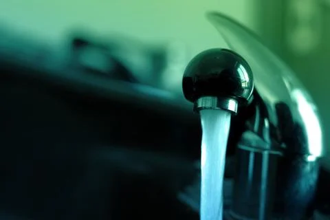Drinking water from the tap in the sink. Stock Photos