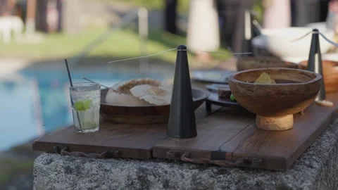 Drinks and Snacks on Wooden Tray Beside Swimming Pool 動画素材 347124976