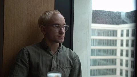 Drinks coffee guy coffee time looks on the window red cup Coffe time, man in t Stock Footage 129195931