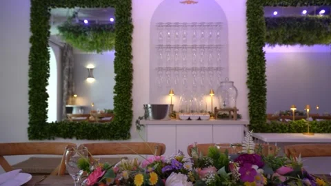 Drinks station with hanging glasses seen past a set dinner table Stock Footage 345551046