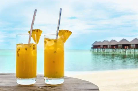 Drinks with a straw on a wooden table on the background of a sandy beach and Stock Photos