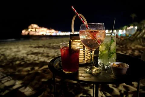 Drinks on a table by the beach at night with city lights in the background Foto stock