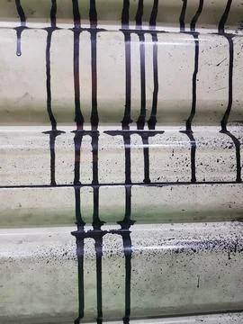 Drip and melt pattern of black paint on a pale yellow background. 库存照片