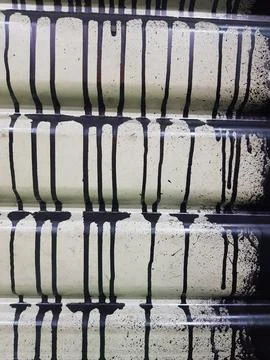 Drip and melt pattern of black paint on a pale yellow background. Stock Photos