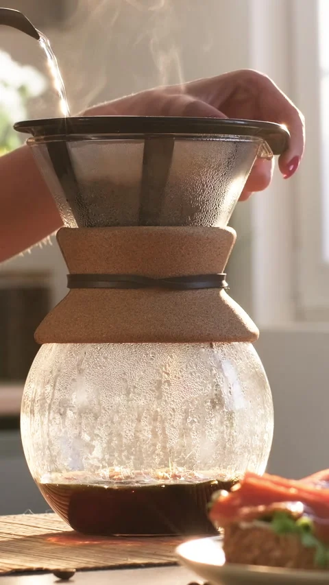 Drip brewing. Young woman preparing drip coffee pouring water from a kettle Stock Footage 309136920