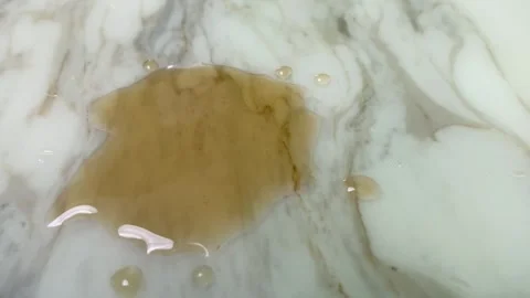 Drip of brown liquid stain on white marble table surface splashing close up Video stock 249243439
