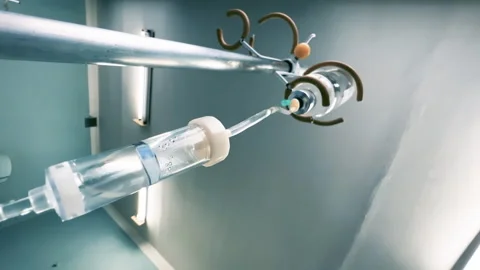 Drip chamber of a IV with dropper bottle on a medical infusion stand in a clinic Stock Footage 260853778