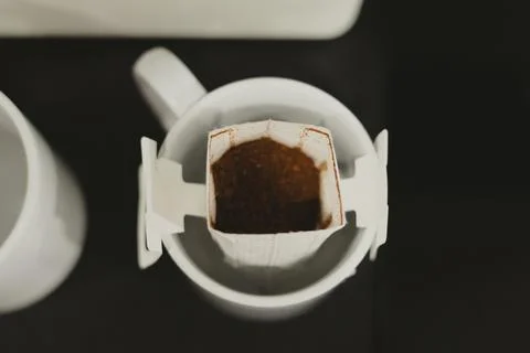 Drip coffee brewing. Two white coffee mugs, one with a coffee bag ready to brew Stock Photos