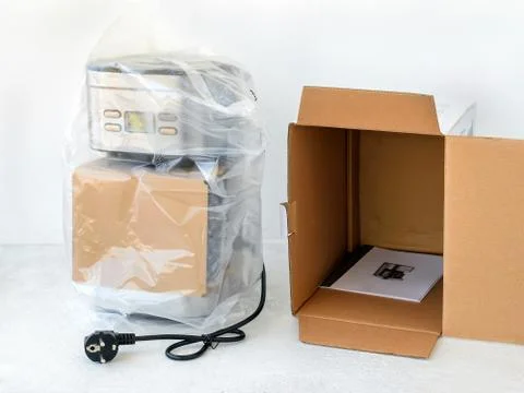 Drip-type coffee maker is in cellophane and near its cardboard box. Stock Photos