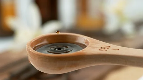 Drip of vanilla extract splashing in measuring spoon, slow motion.  Shot on Vidéo 130359442