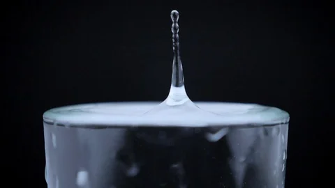 Drip of water dropping in glass filled with water, black background, high Video stock 91874121